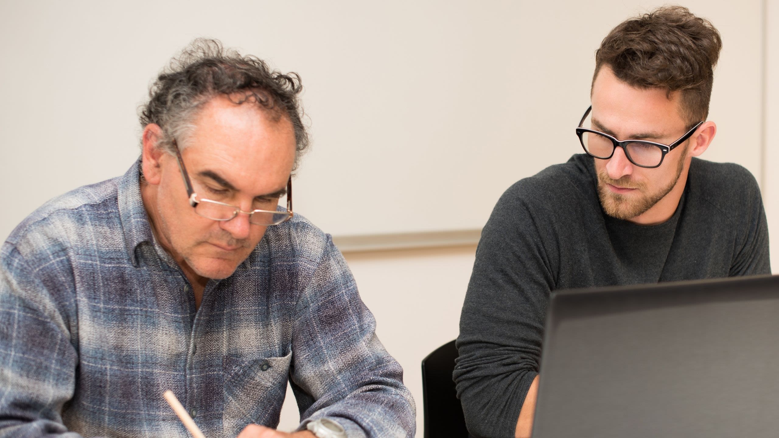 Image of student working with older man in the community on computer skills